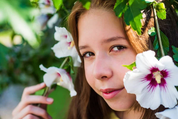 アロマ。夏のファッションと美しさ。ハイビスカスの茂みの花を持つ美しい10代の女の子。子供の春ファッションスタイル。幸せな子供時代。屋外の木の開花時に明るい子供。休暇の時間 — ストック写真