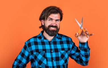 Bıyıklı ve sakallı yakışıklı hippi. Makas, berber dükkanı gibi kuaför aletleri kullanıyor.