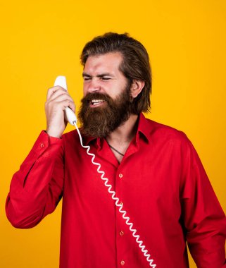 Modern görünümlü sakallı hippi telefonda konuşuyor. İletişim konsepti. Bıyıklı vahşi yakışıklı adam klasik telefon kullanıyor. Olgun yönetici ya da asistan. Konuşma. Doğrudan Ol