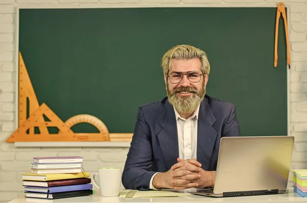 Teach and inspire. Senior teacher sit at desk. Bearded man back to school. Formal education. Education and study. Education course. Online education. Teaching and learning. E-learning. New technology