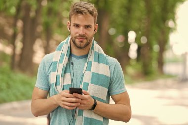 Aktif yaşam tarzın için telefon. Fit adam cep telefonundan müzik dinliyor. Antrenman ve spor eğitimi için telefon uygulamaları kullanıyorum. Modern hayat. Yeni teknoloji. Forma girmek için telefonunu kullan.