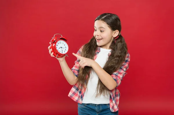 Здивована дівчина-підліток показує час на ретро будильник, продажі — стокове фото