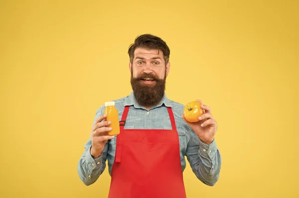 Entregando vitaminas frescas. Bebida de batido Hipster. Jugo fresco. Un batido exprimido. Hombre barbudo chef mantenga orgánico tomate natural y botella de fondo amarillo. Nutrición vegetariana. Bebida de batido — Foto de Stock