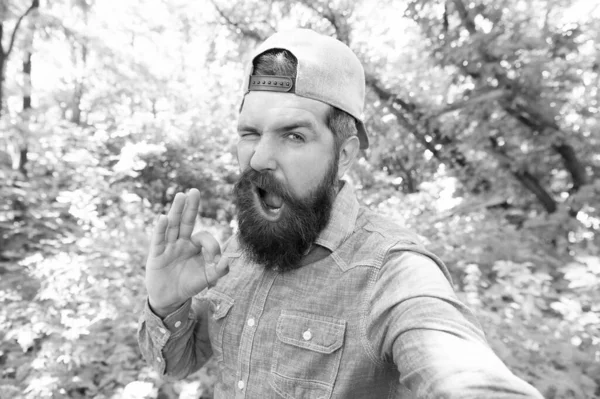 Erkek gösterisi Tamam jest. Ormandaki vahşi hippi. Yeni yerler keşfet. Piknik zamanı. Bıyıklı, beyaz bir adam. Olgun sakallı adam selfie çeker. Yaz kampı tatili. Hippi yürüyüşü. — Stok fotoğraf
