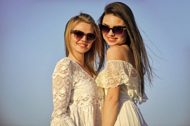 Ortak gezi. Yazlık kıyafet. Güzel kızların portresi. Plaj tarzı. Yazın açık hava yaşam tarzı. Mavi gökyüzünde poz veren mutlu genç arkadaşlar. Güneş gözlüklü güzel genç kadınlar.