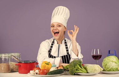 Mükemmel. Mutlu gülümseyen şef çeşitli sebzelerle yemek hazırlıyor. Yeni yemek yapmaya hazırım. Taze vejetaryen salatası. Ticari mutfakta aşçı. Sağlıklı ürünleri olan profesyonel bir şef.