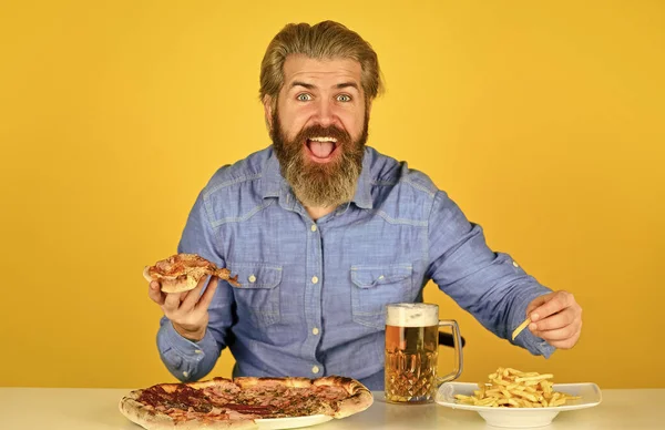 Wesoły brodaty hipster je pizzę. Koncepcja pizzy. Dostarczanie szczęścia do ust. Piwo i jedzenie. Kolacja w pubie. Głodny człowiek będzie jadł pizzę i pił piwo. Restauracja Pizzeria — Zdjęcie stockowe