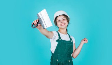 İnşaat üniforması ve sıva spatulası kullanan neşeli çocuk işçiler.