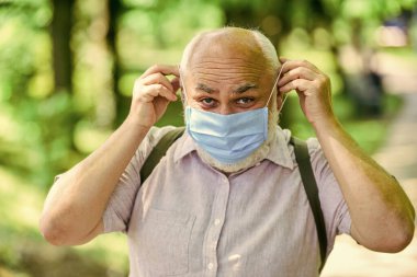 Sıcak bir gün. Park koronavirüs nedeniyle karantinaya alınmıştır. Solunum maskeli yaşlı adam. Baharın tadını çıkarın. Koronavirüs kovid 19. Bahar keyfi. kısıtlı park