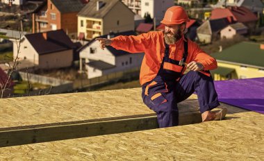 Adam ev inşa ediyor. Düz çatı kurulumu. Çatı keçesi. Özel korumalı Roofer işçisi. İnşaat binasının altındaki yeni çatı. İnşaatçı çekiç kullanır. profesyonel tamir çatısı