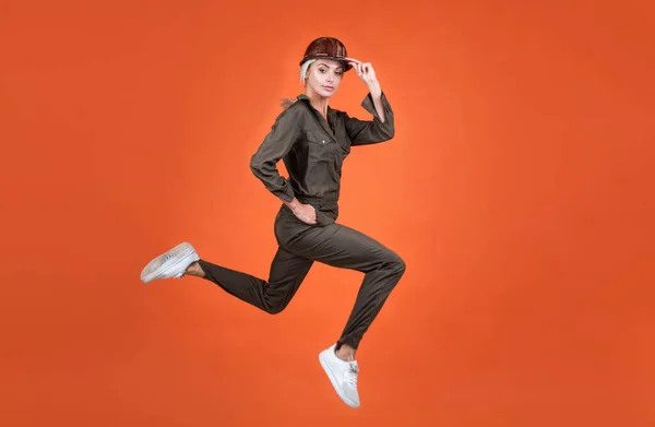 Woman in boiler suit and helmet jump. umping builder hurry up on work. building and construction concept. sale on service. lady worker running. full of energy. stamina. fast and quality service — Stock Photo, Image