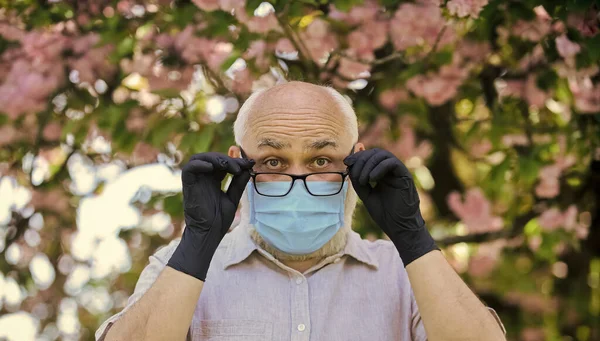 Immuunsysteem is minder effectief in het bestrijden van infecties als we ouder worden. Senior man draagt gezichtsmasker en handschoenen buiten. Hoe senioren te helpen. Senioren lopen vooral risico als ze geïnfecteerd zijn. — Stockfoto