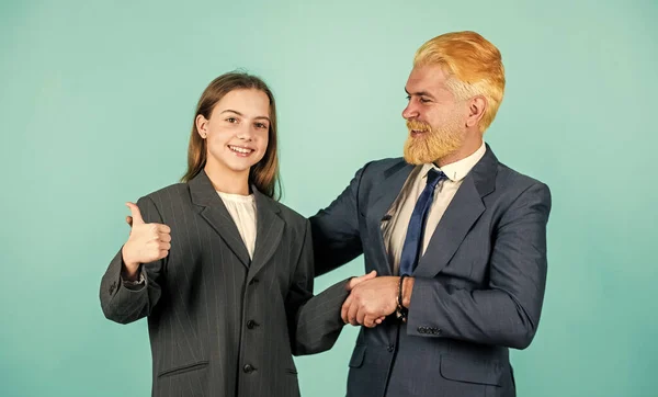 future career. family business. partnership. teamwork of daughter and dad. business meeting. modern office life. businessman dyed blond hair. small girl in oversized suit jacket