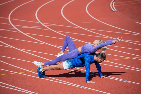 Спорт фітнес чоловік і жінка тренуються разом стояти на дошці і підштовхуватися до гоночної траси на відкритому стадіоні в спортивному одязі, спортивні тренування — стокове фото