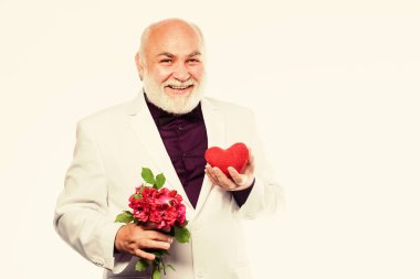 Adam sevginin kalp sembolünü taşıyor. Yaşlılar için flört hizmetleri. Centilmen kavramı. Gerçek bir beyefendi. Yakışıklı sakallı adam smokin giyer. Romantizm ve flört. Yaşlı centilmen romantik ruh