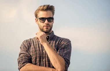 Ultraviyole koruma kavramı. Erkek gözlüklü model açık havada mavi gökyüzü arka planı. Mükemmel görüş. Net olarak gör. Yakışıklı adam güneş gözlüğü takıyor. Moda güneş gözlüklü hippi. Moda güneş gözlüğü.