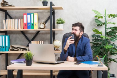 Formalite icabı uykucu yönetici sabahları büro masasında kahve içer, içki içer.