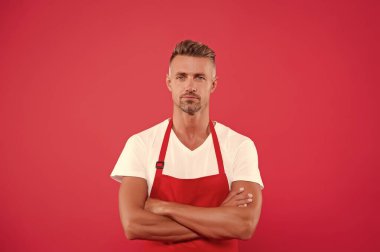 Önlüklü olgun bir adam ellerini çapraz yaptı. Restoranın hostesi. Fast food restoranı. Restoran personeli. Üniformalı adam. Mesleki yaklaşım. Kafemize hoş geldiniz.