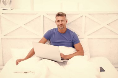 Bir şeyler alıp internetten alışveriş yapmak. Adam yatakta bilgisayar kullanıyor. İletişim ve insan konsepti. Çevik iş. Sabah titreşimleri. Adam dizüstü bilgisayarda çalışıyor. Online kurslar evde eğitim. İpuçlarını kilitle