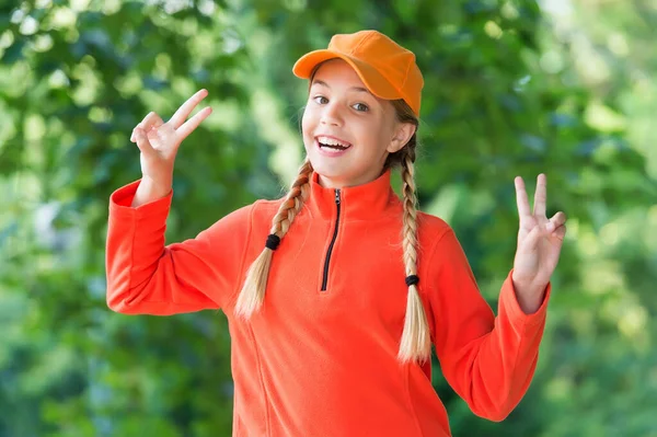 Das Leben macht Spaß. Glückliches Mädchen Kind zeigen Friedenszeichen im Freien. Beauty-Look. Modetrend. Trendiger Stil. Kinderbetreuung und Kindheit. Internationaler Kindertag. 20. November — Stockfoto