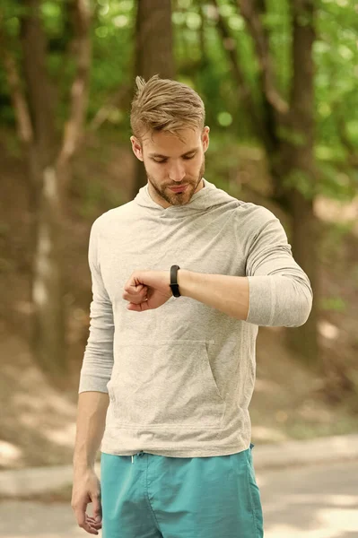 Aktif yaşam tarzı için ideal bir saat. Atletik adam nabzını kontrol ediyor. Yakışıklı sporcu antrenman sırasında akıllı saat kullanır. Fitness takibi. Saatli spor antrenmanı. Teknoloji ve spor