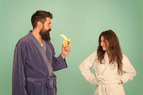 Erotic games for couple. Couple in love blue background. Sensual couple. Sexy woman look at bearded man eating banana. Blowjob and desire. Mens health and potency. Family couple in home clothing — 스톡 사진