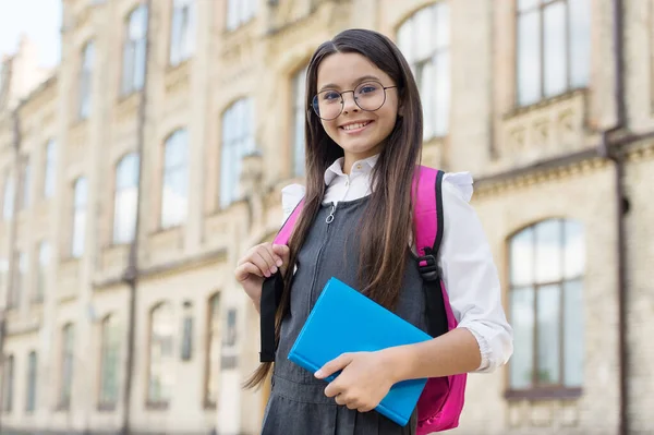 Bugün iyi öğren. Gözlüklü mutlu çocuk kitap ve sırt çantası taşıyor. Okulun gerekliliklerine dönelim. Okul kütüphanesi. Bilgi toplama günü. Resmi tarz. Moda üniforması. İlkokul eğitimi. Başla. 1 Eylül