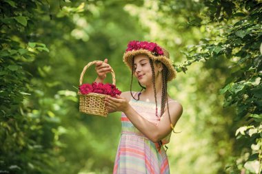 Doğanın bir parçası. Bir buket gül çiçeğiyle göz kamaştırıcı bir kız. Hasır şapkalı mutlu çocuk. Doğanın saç stili. Anneler Günü. Mutlu kadınlar günü. Çiçekli küçük bir çocuğun portresi. Aşk ve güzellik