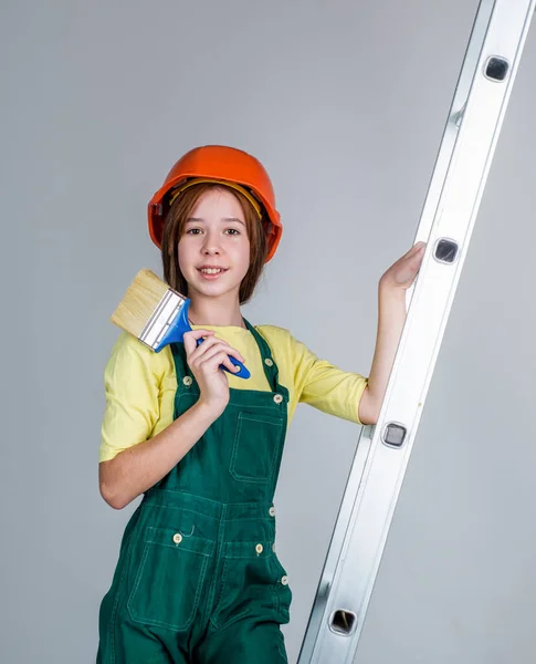 はしごや労働の日に筆で作業をしながら制服やヘルメットを着た女の子 — ストック写真