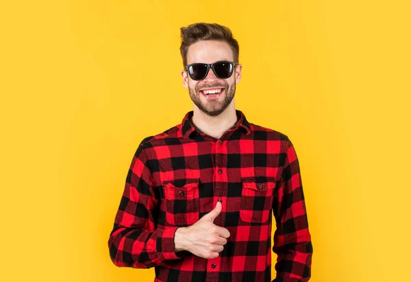 Jovem homem bonito em camisa quadriculada e óculos de sol tem cerda no rosto, férias — Fotografia de Stock