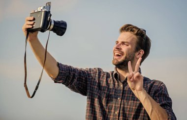 Blogger video blogu çekiyor. Tatil zamanı. Yakışıklı blogcu, gezgin, geçmişe dönük kamera. Adam açık havada gökyüzü arka planında. Fotomuhabir konsepti. Gezgin blogcu. Gazeteci fotoğraf çekiyor. Antika ekipman