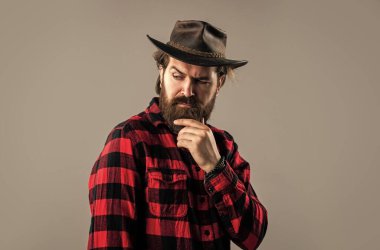 Erkek güzellik standartları. Kendine güvenen ve yakışıklı vahşi bir adam. Yüz bakımı. Sakallı hippi. Bıyıklı, vahşi, beyaz bir hippi. Erkek berber bakımı. Kovboy şapkalı sakallı adam. Saç ve sakal bakımı