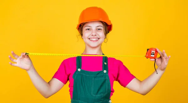 This will be perfect. kid wear helmet on construction site. teen girl builder with building tool tape measure. child on repairing work. concept of renovation in workshop. busy professional carpenter — Stock Photo, Image