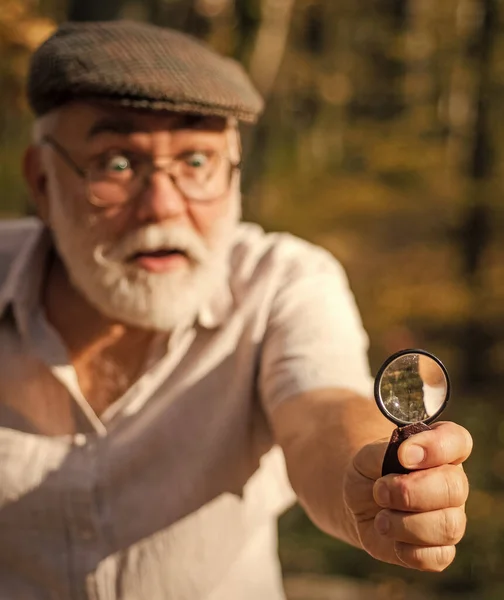 Sehen Sie klar. Lupe oder selektiver Fokus aus Glas. Objektiv und optisches Werkzeug. Ein alter Mann blickt durch eine runde Linse nach draußen. Handlinse. Die Natur untersuchen. Vergrößerung und Untersuchung. Naturbeobachtung — Stockfoto