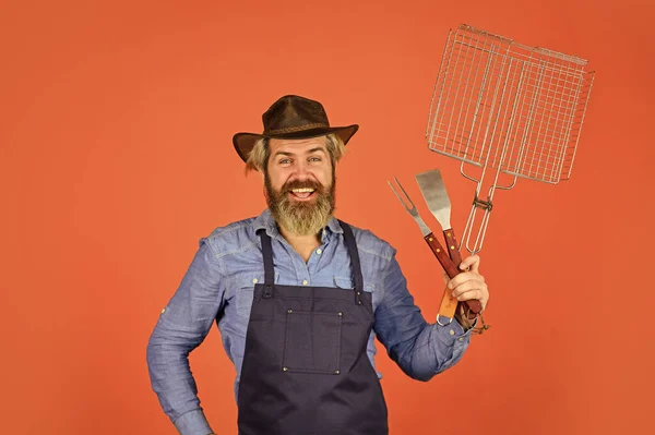 Piknik és barbecue. A szakállas farmer kalapot és kötényt visel a grillezéshez. Húst sütök. Steak és barbecue. Grillezett. Grillezés. Amerikai piknik. Családi hagyomány. Húst főzök. Tavaszi szezon — Stock Fotó