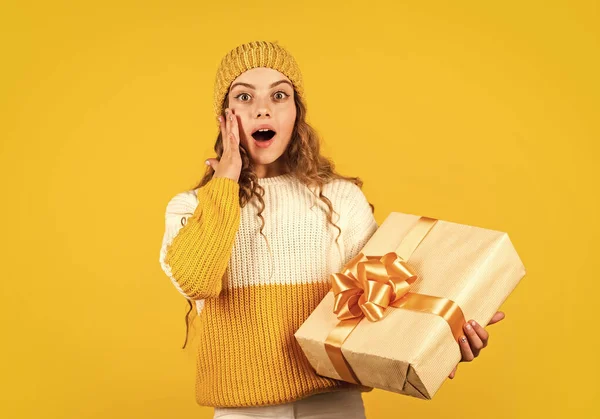 Niño niña sostiene caja de regalo con cinta sobre fondo amarillo. Regalo de Navidad para hija. Disfruta de las sorpresas. Chica adolescente recibió regalo de vacaciones. Los mejores regalos de Navidad. Niño emocionado desembalaje regalo — Foto de Stock