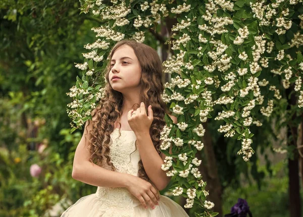 Adorable moment. wedding angel kid. child enjoy jasmine flower in park. spring blooming tree. summer nature. female hairdresser fashion. small girl with long curly hair. little beauty in white dress — Stock Photo, Image