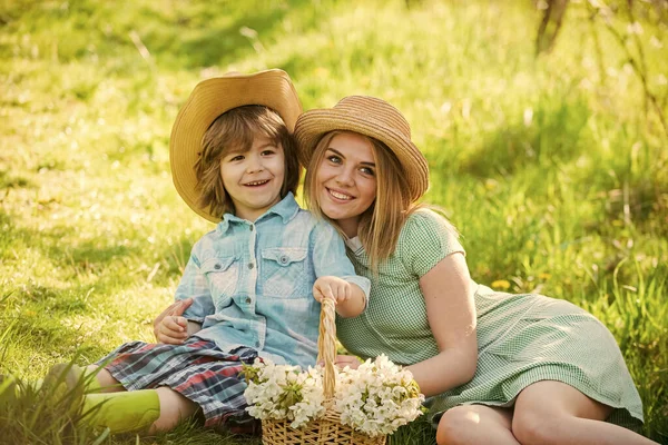 Spring season. Happy holidays. Mother and cute son having fun. Spring holiday. Weekend leisure. Explore nature. Wildflowers in field. Motherhood happiness. Cowboy family collecting spring flowers