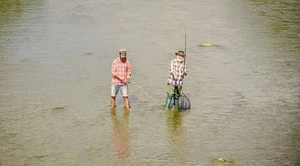 Foi pescar. hobby e atividade esportiva. Isca de truta. dois pescadores felizes com vara de pesca e rede. pesca de pai e filho. Aventuras. Grande jogo de pesca. amizade masculina. recreação e lazer ao ar livre — Fotografia de Stock