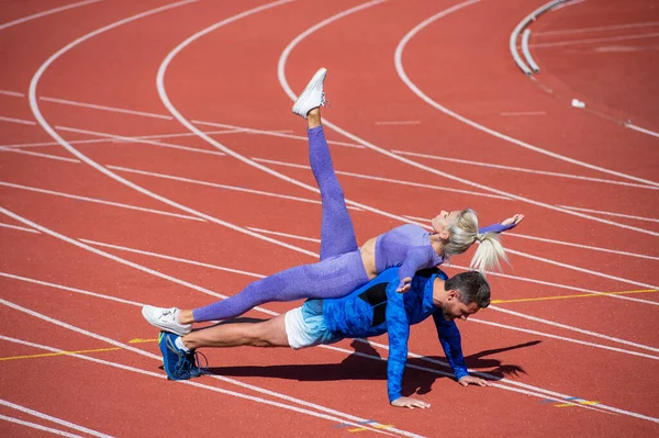 运动健美夫妇一起站在跳板上，穿着运动服、运动健美，在室外体育场赛马场上奔跑 — 图库照片