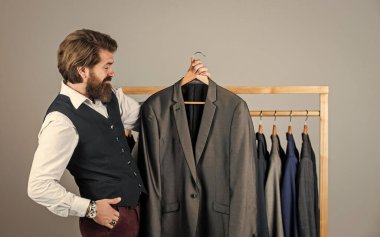 Müşterilerle temas halinde. Kendine güvenen terzi erkek ceketi tasarlıyor. Mezura takan yakışıklı bir sartor. Erkek güzellik ve moda. Sakallı adam, terzi kıyafetleri. Resmi ve ofis kıyafetleri. İş adamı