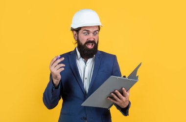 Proje üzerinde çalışıyorum. bina konsepti. Başlık takan mühendis ya da inşaatçı. Miğferli olgun bir mimarın not almasına şaşırdım. Vahşi sakallı adam belgelerle inşaat alanında çalışıyor.