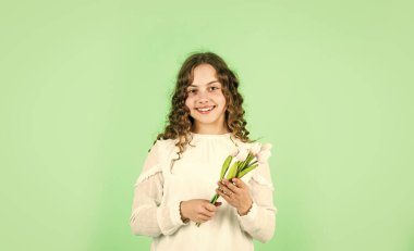 En iyi doğal hediye. Anneler Günü konsepti. Kıvırcık saçlı neşeli küçük kız. Çocuk için lale çiçeği. Mutlu kız lale çiçeklerini tutar. Bahar buketi. Mutlu kadınlar günü. Uluslararası Çocuk Günü