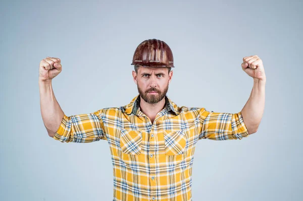 Schöner Mann Bauarbeiter in Bauhelm und kariertem Hemd demonstriert Macht auf Baustelle, männliche Stärke — Stockfoto
