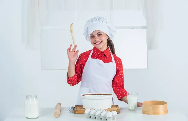 Faire du gâteau par recette. C'est l'heure de manger. cuisine enfant heureux dans la cuisine. cuire les biscuits dans la cuisine. boulanger professionnel et qualifié. Enfant en uniforme de chef et chapeau. adolescent fille préparation pâte — Photo