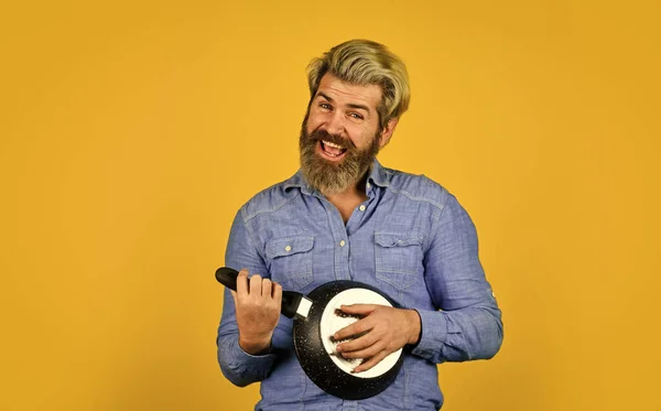 Cuisiner dans la casserole. pour la préparation des aliments. Homme barbu cuisinant dans la cuisine. culinaire et gastronomique. Des ustensiles de cuisine. Cuisine saine. cuisine plat savoureux. barbu homme jouer guitare poêle à frire — Photo