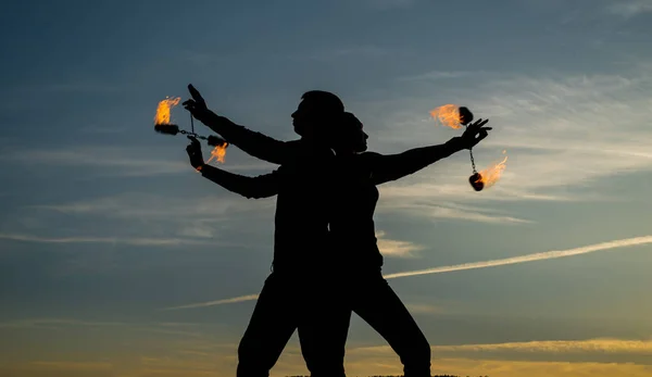 Tänd din dansande låga. Dansande par snurrar brinnande poi. Flamdansare på idyllisk himmel. Kväll nyanser och ljus. Eldgivning. Utomhusfestival. Nattfest. Kul och underhållning — Stockfoto