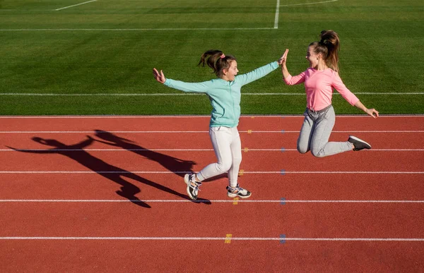 Divertente sano bambini ragazze allenamento fitness su pista da corsa stadio, successo sportivo — Foto Stock