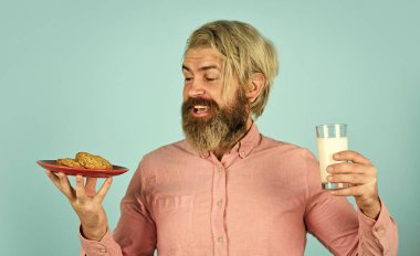 Süt ve kurabiye. Mutlu çiftçiler tatlı yer. Sakallı adam hamur işiyle yararlı süt içer. Sağlıklı beslenme kavramı. Kahvaltı veya öğle yemeği için organik tarım ürünleri