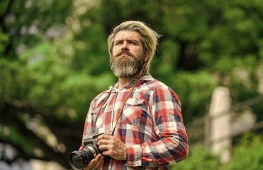 Profesyonel fotoğrafçı klasik kamera kullanır. Sakallı hippi adam fotoğraf çekiyor. Retro kameralı acımasız bir adam. Modern iş. Fotoğrafçılık işi. Eski teknoloji. Gazeteci gazeteci.